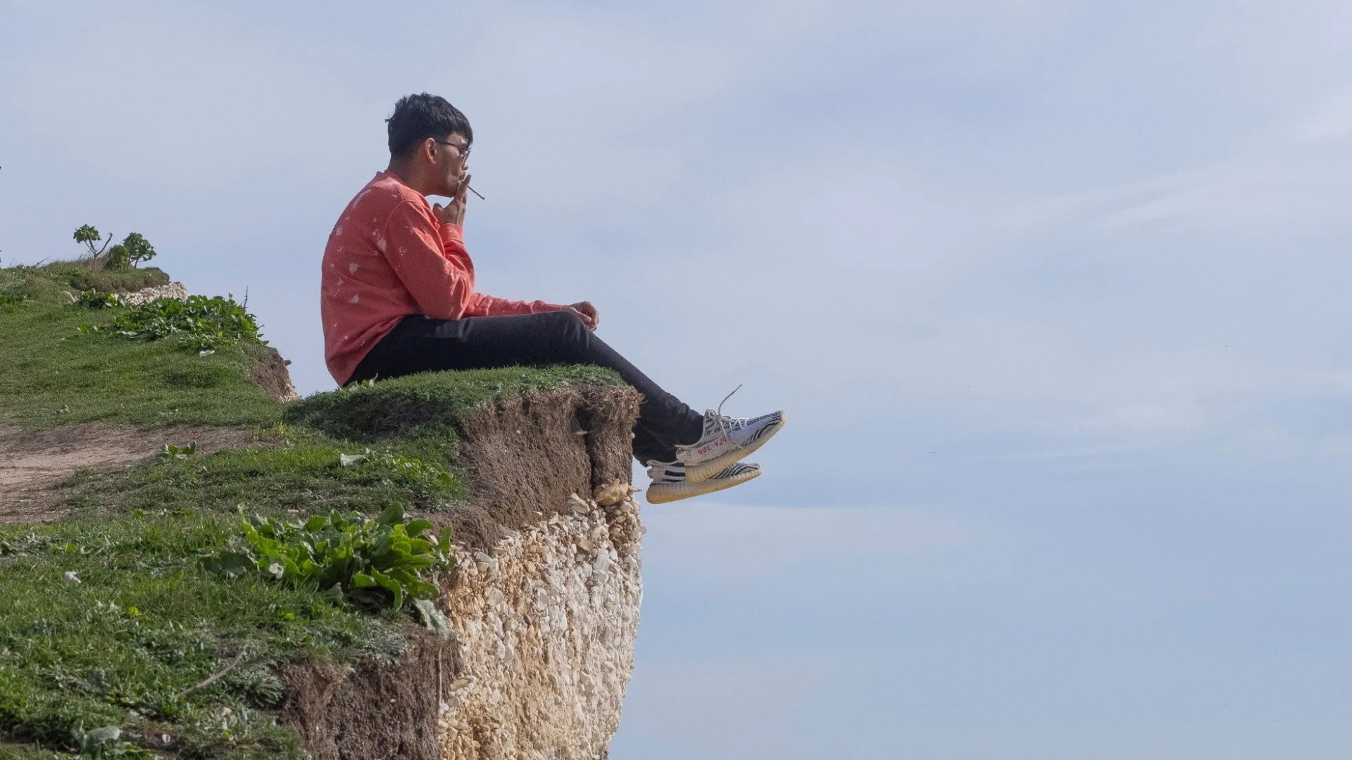 Smoker dangles legs over edge of 400ft cliff despite warning it’s crumbling [Video]